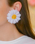 all-groups Femme blanche brune portant des grandes boucles d'oreilles fantaisie marguerite