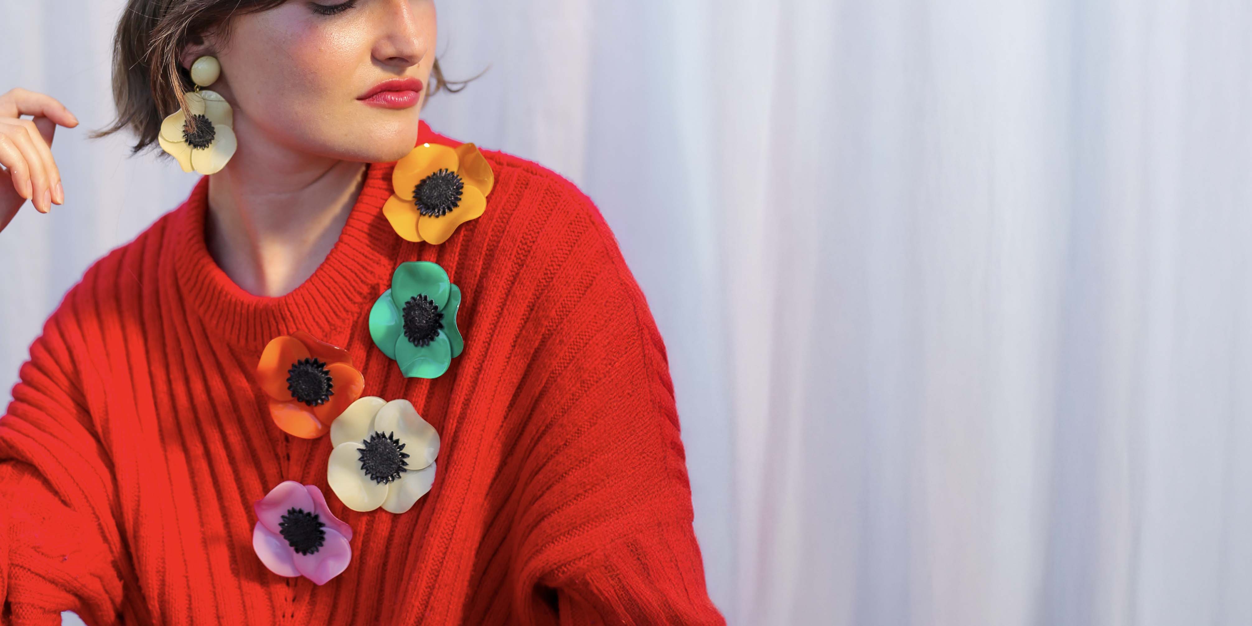 Grandes broches colorées portées sur un pull rouge