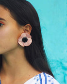 Grandes boucles d'oreilles roses portées sur femme aux cheveux bruns