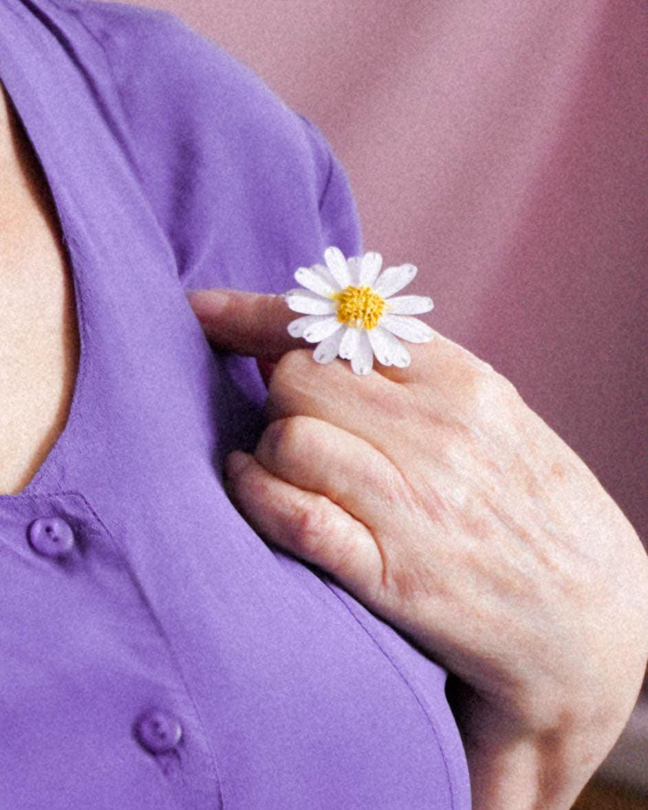 Main de femme portant une robe mode violette et une bague fleur marguerite blanche