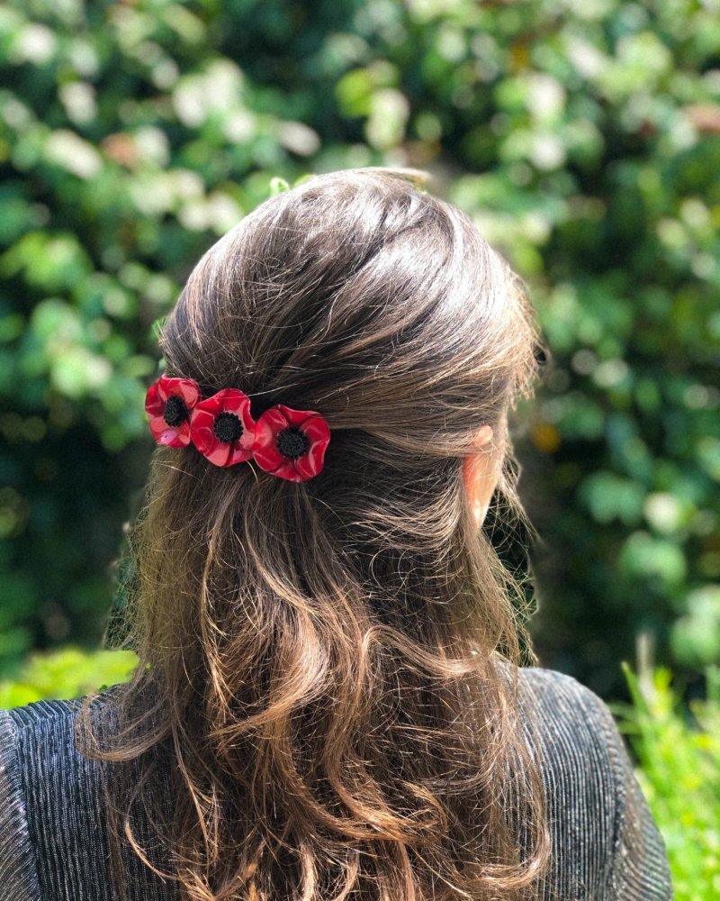 all-groups femme dans la nature portant une barrette cheveux trois fleurs rouge