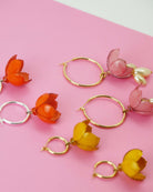 boucles d'oreilles diverses posées sur un fond rose all-groups