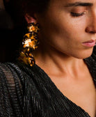 all-groups Femme portant une robe en lurex plissée et des boucles d'oreilles statement avec trois fleurs motif léopard