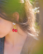 Femme dans la nature portant des bijoux d'oreilles en forme de cerises rouges