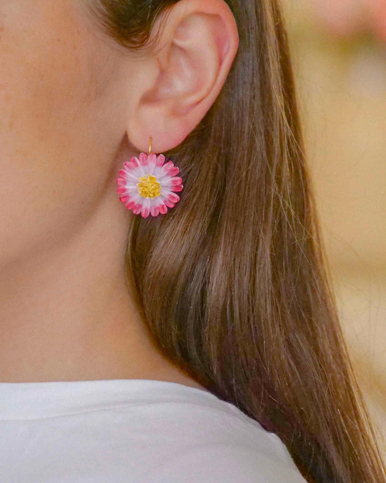 all-groups Femme portant des petites boucles d'oreilles fleurs marguerites roses et blanches