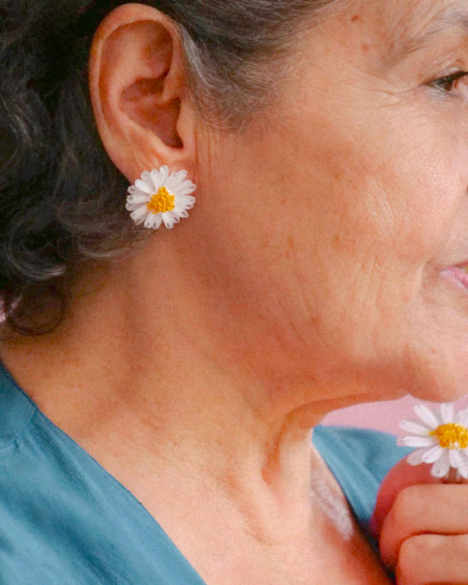 all-groups Femme agée portant des petites boucles d'oreilles puces marguerite blanches