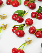 Plein de boucles d'oreilles cerises rouges posées sur un fond blanc all-groups