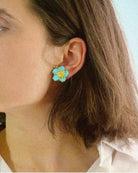 all-groups Femme blanche brune portant des boucles d'oreilles fleurs turquoise