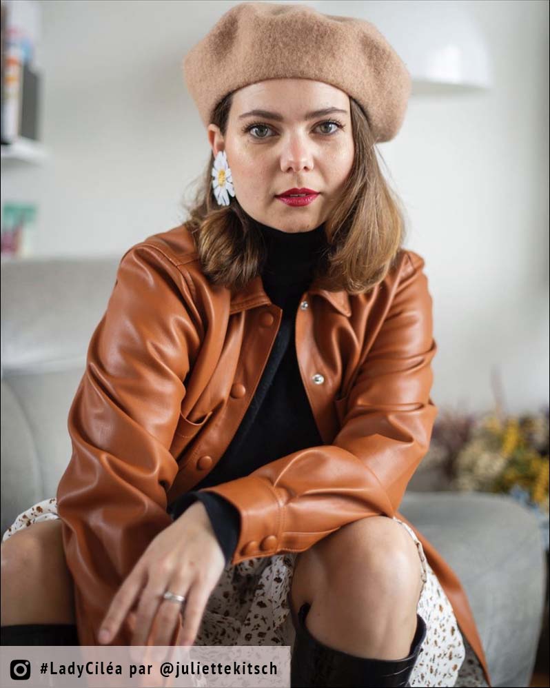 femme portant une veste en cuir avec des grandes boucles d'oreilles marguerites