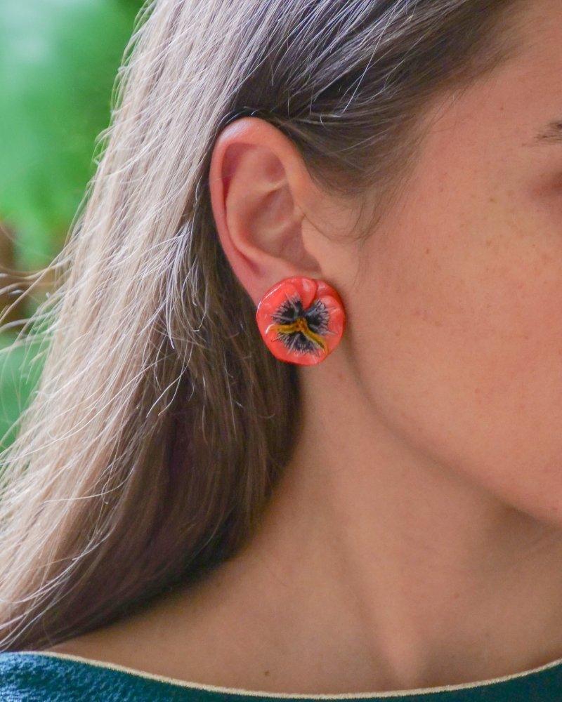 all-groups Femme portant des petites boucles d'oreilles en forme de fleurs oranges