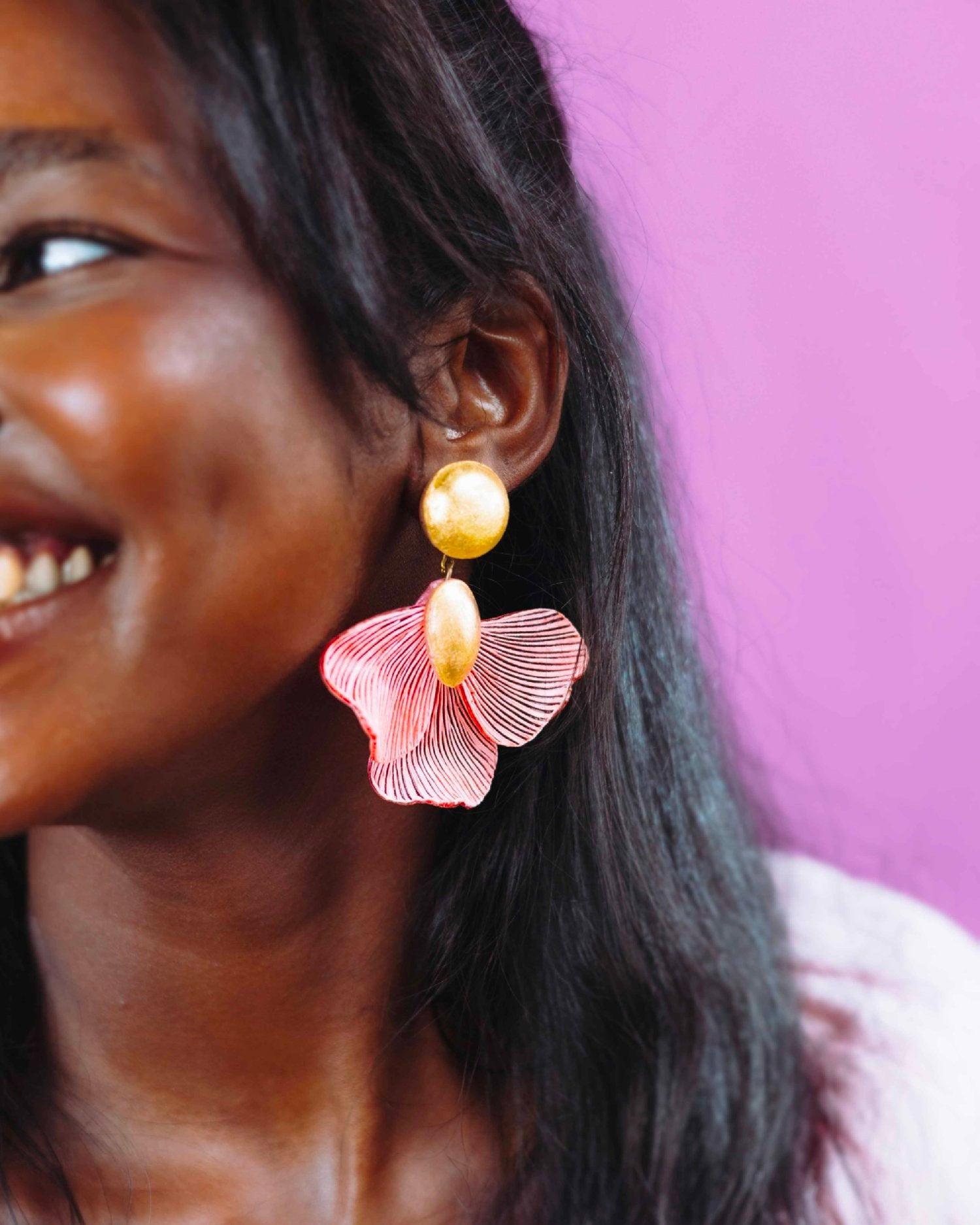 all-groups Femme souriant aux cheveux longs noirs portant des boucles d'oreilles rose et or