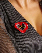 all-groups Broche fleur rouge portée sur un décolleté en lurex gris brillant 