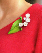 all-groups Bijou muguet blanc avec feuilles vertes sur pull rouge