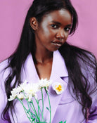 all-groups Femme noire portant un blazer violet des fleurs et une broche blanche fleurie