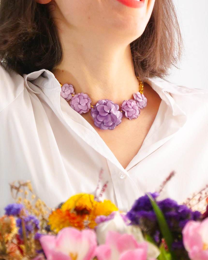 all-groups Femme avec une chemise blanche qui porte un collier fleur violet