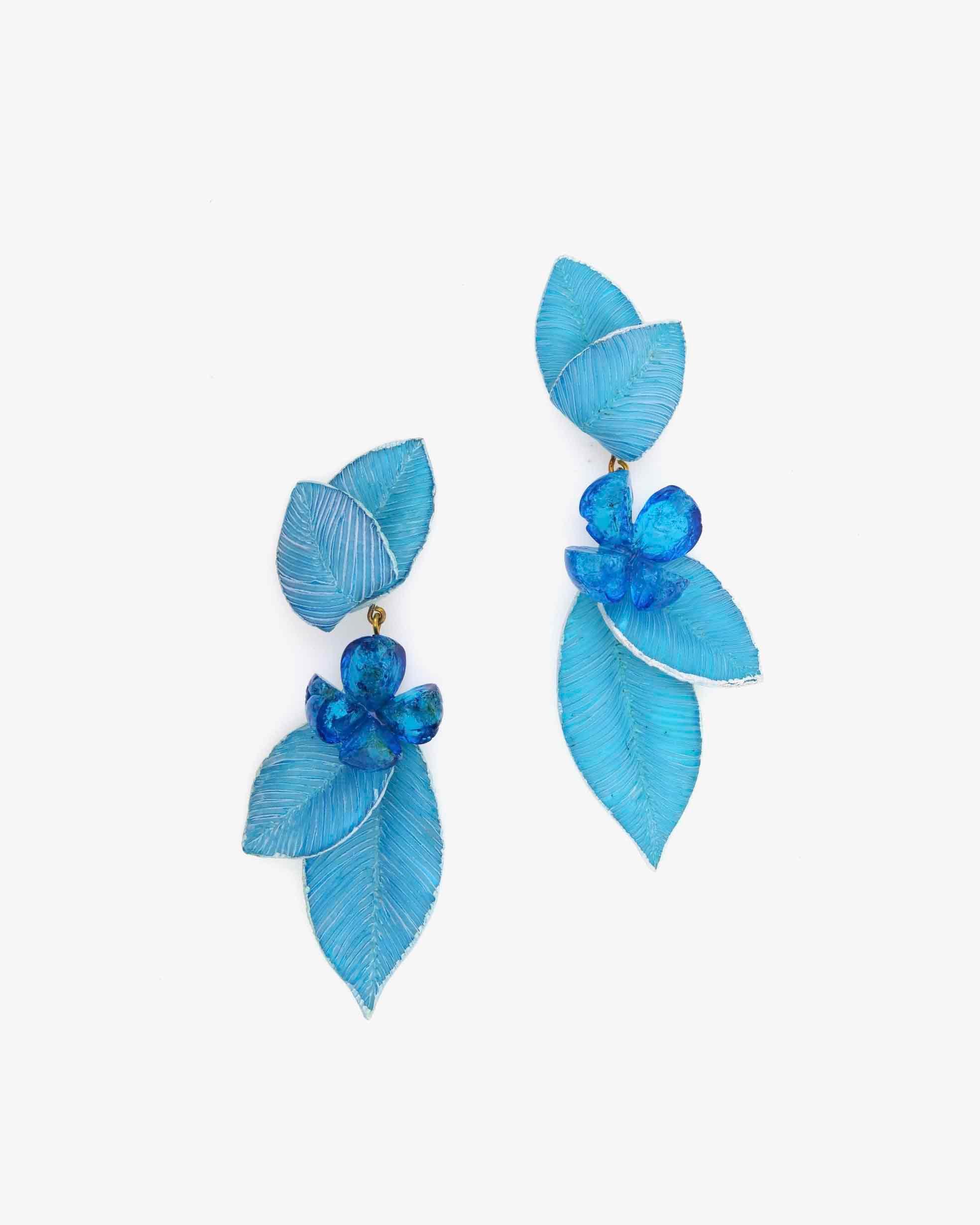 boucles d'oreilles pendantes bleues avec fleur brillante au milieu