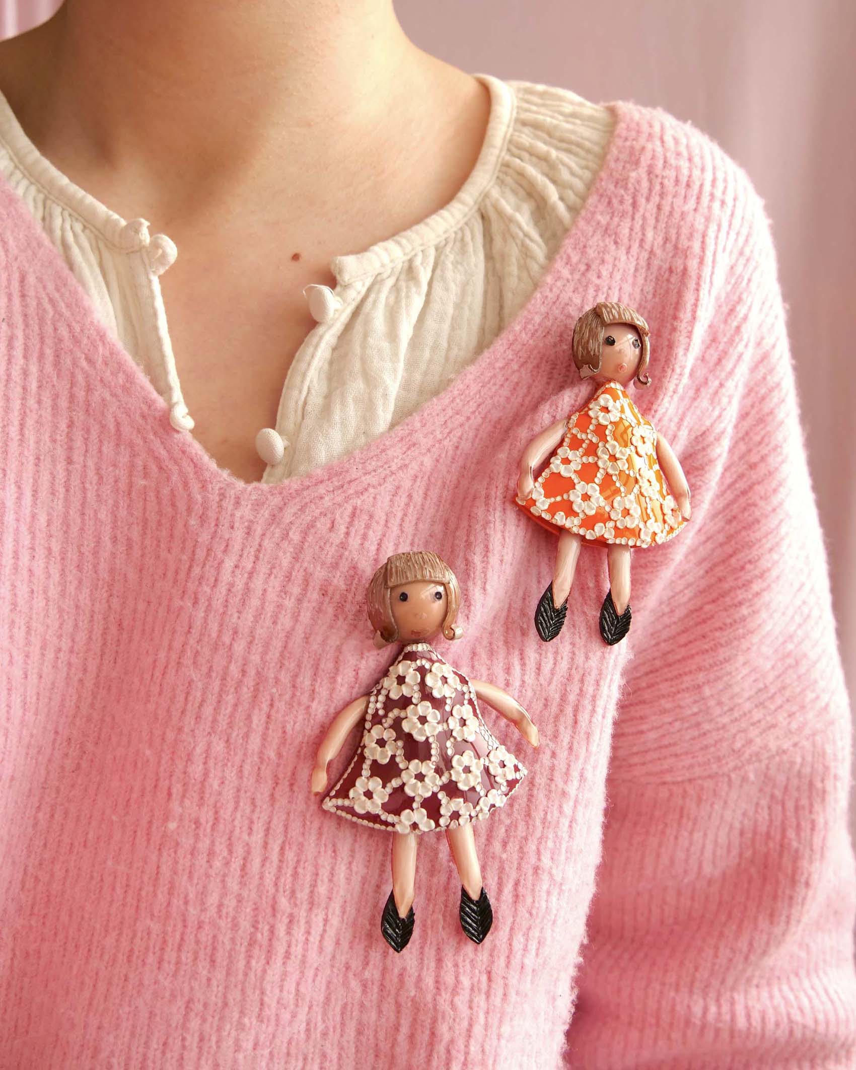 all-groups Femme portant 2 broches petite fille sur un pull rose 